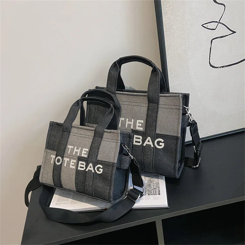 Two gray tote bags with 'THE TOTE BAG' text on a black surface.