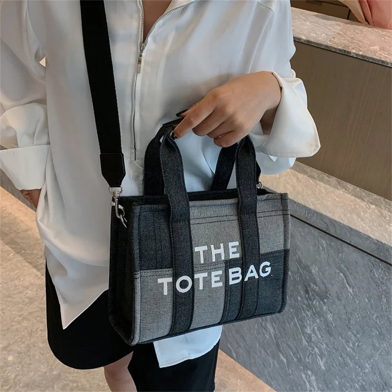 Person holding a gray tote bag with 'THE TOTE BAG' text.