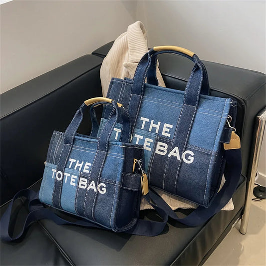Two blue tote bags with 'THE TOTE BAG' text on a black surface.