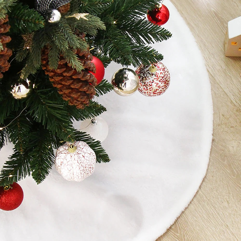 Christmas presents wrapped in kraft paper tied with red string sitting on a white faux fur tree skirt.